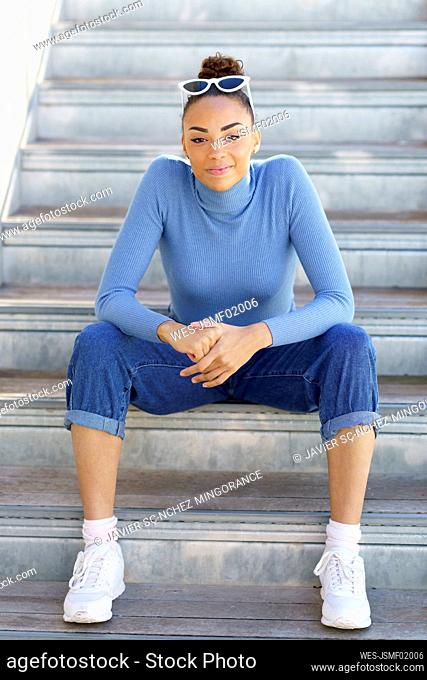 Smiling woman staring while sitting on steps