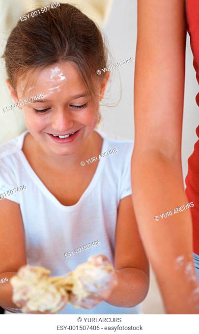Young girl holding dough in her hand and playing with it