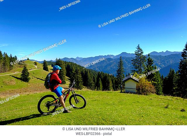 Germany, Mountainbiker looking to Hirschtalsattel, Aueralm with Tegernsee Mountains near Lenggries