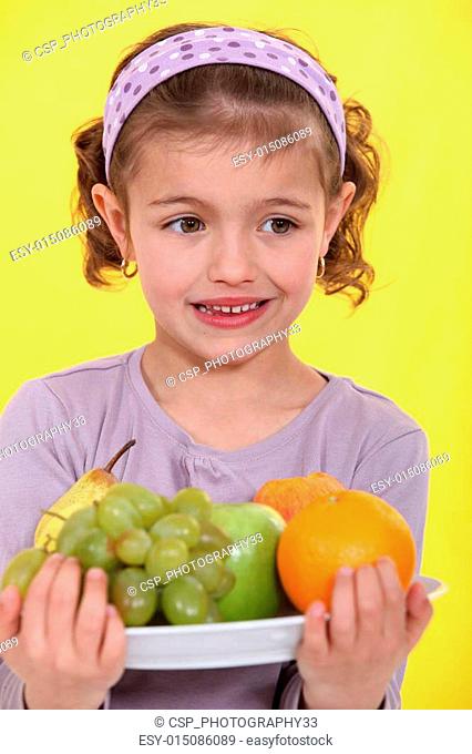 Little girl with an armful of fruit