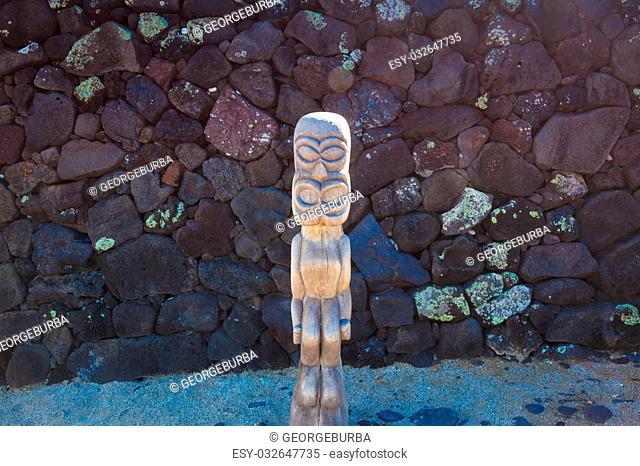 Old wooden protection idol with black lava stone background at an ancient Hawaiian site Pu’uhonua O Honaunau National Historical Park on Big Island, Hawaii