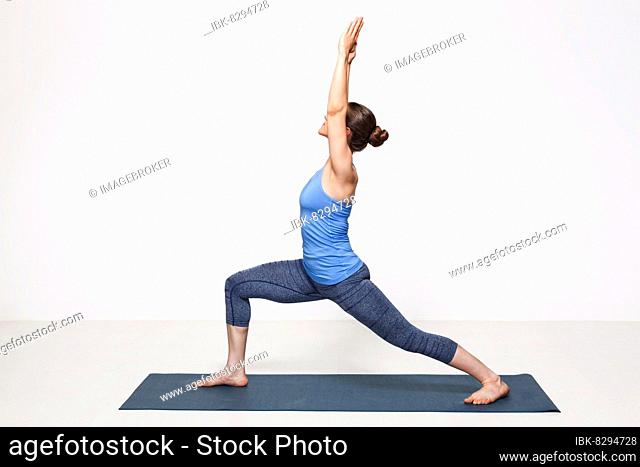 Beautiful sporty fit yogini woman practices yoga asana Virabhadrasana 1, warrior pose 1