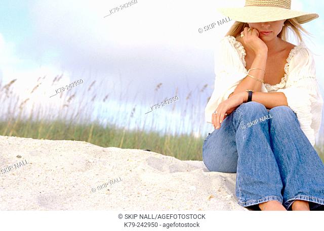 Young woman on sand dune thinking
