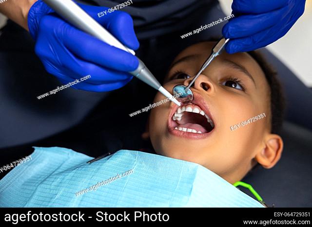 In dentistry. Dark-skinned boy looking scared of medical tools