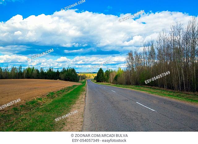 asphalt road in a beautiful natural landscape against a blue sky with clouds on a sunny spring day. route in the countryside, travel