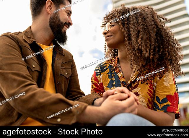 Happy young man holding hands of girlfriend