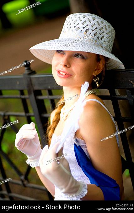 Young lady wearing white hat sitting on bench in park