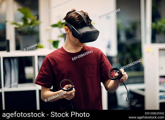 Young man in virtual reality goggles, vr glasses headset with joystick