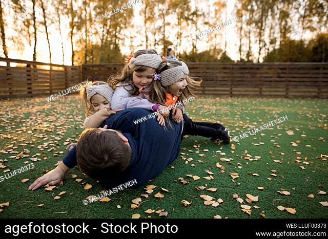 Siblings playing with father at lawn in autumn