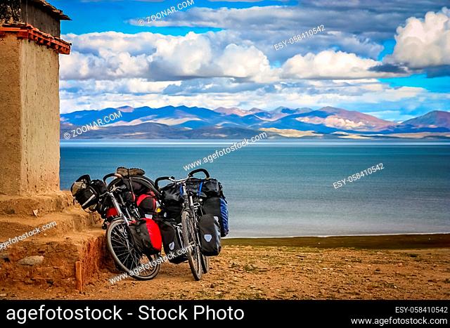 Two cycle touring loaded bicycles rested on the wall of a small old tibetan monastery on a hill above holy Lake Manasarovar, Tibet, China