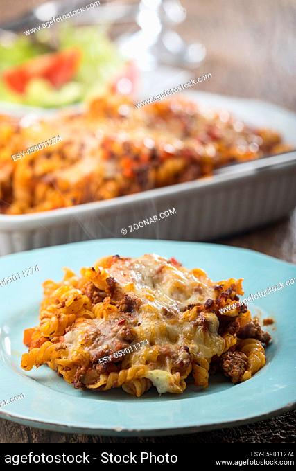 gratinated pasta with salad on wood