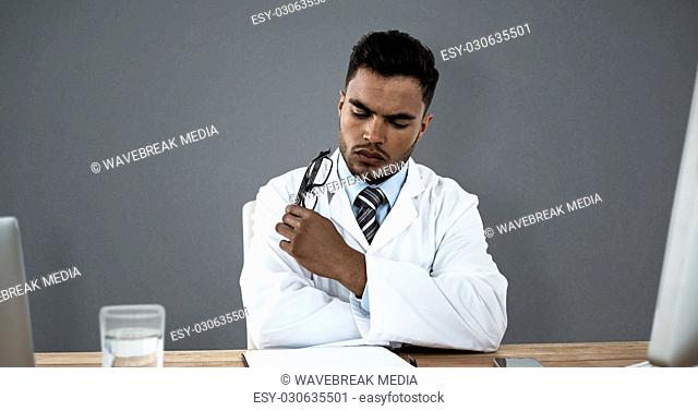 Composite image of doctor looking medical report at desk