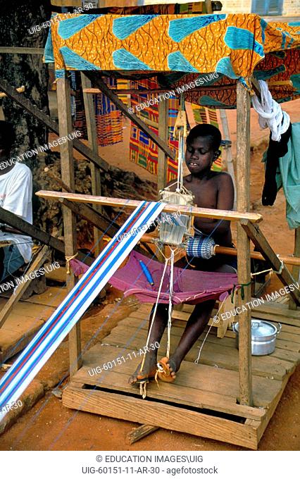 A young boy weaving traditional kente cloth, a textile worn by royalty