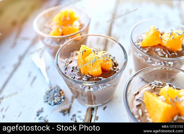 Ayurvedic cuisine - chocolate mousse with silken tofu, decorated with orange fillets and lavender flowers, filled small glass bowls stand on a white wooden...