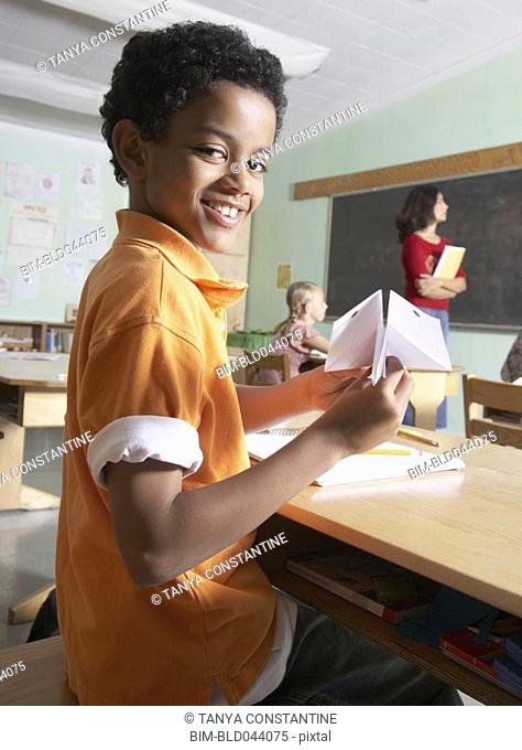 Mixed Race boy holding paper airplane in class
