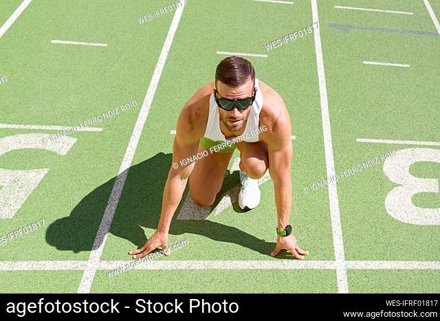 Man sitting in ready position on running track
