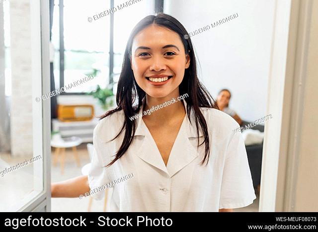 Smiling woman opening door at home