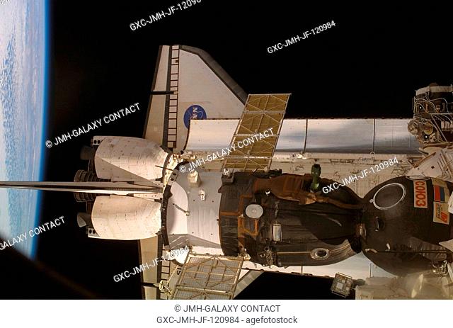 Backdropped by the blackness of space and Earth's horizon, the docked Space Shuttle Atlantis (STS-117) and a Soyuz spacecraft are featured in this image...
