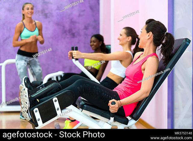 Full length side view of a fit woman laughing while listening to the instructions of a qualified fitness instructor, with sense of humor during group class for...