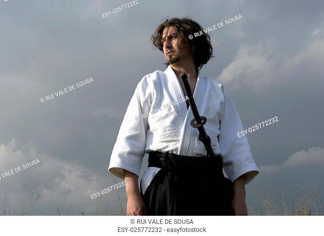 young aikido man with a sword, outdoors