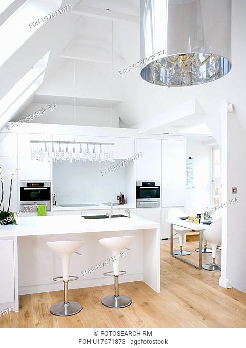 White Bomba stools at breakfast bar in modern white loft conversion kitchen with wooden flooring