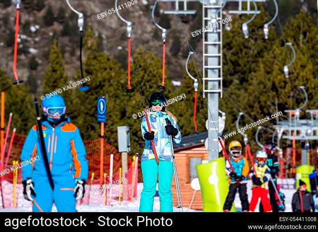 Selective focus on Caucasian white woman, skier riding up on draglift. Winter holidays in El Tarter, Grandvalira, Andorra