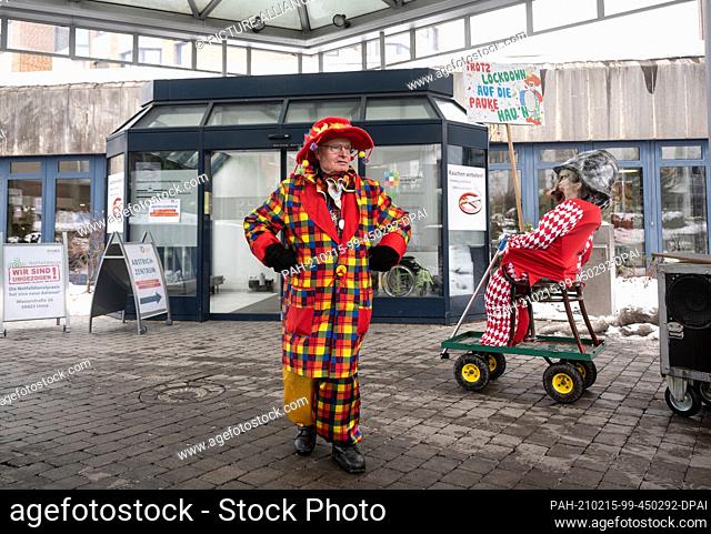 15 February 2021, North Rhine-Westphalia, Unna: Carnivalist Helmut Scherers dances in front of the main entrance of the Christliches Klinikum Mitte during what...