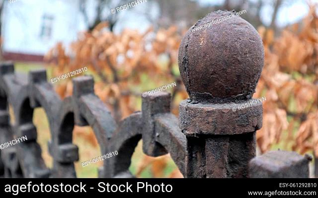 Fragment of a cast-iron fence close-up. An old cast-iron wrought-iron fence with artistic forging against the background of an autumn city park