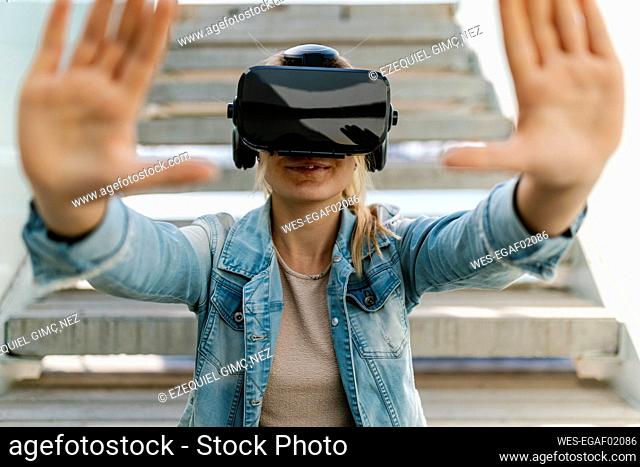 Woman gesturing while watching video through virtual reality simulator