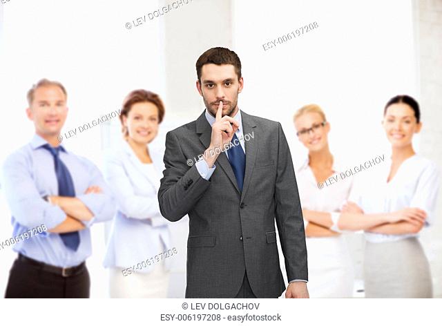 business, office, gesture and people concept - group of smiling businessmen making hush sign in office