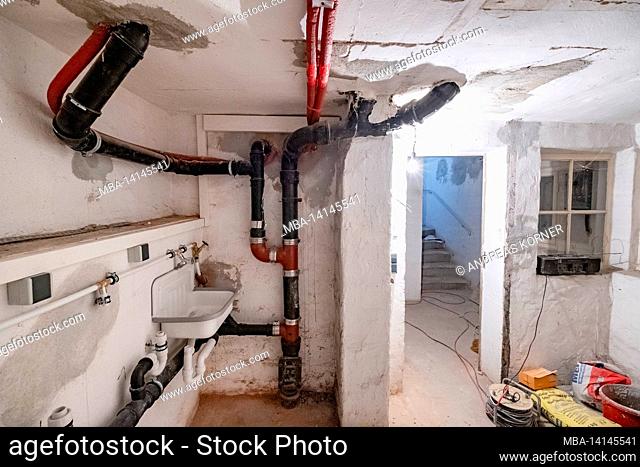 construction site, redevelopment and renovation of an apartment, empty room of a laundry room in the basement with old sewer pipes