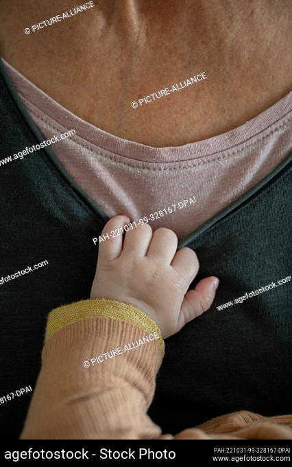 SYMBOL - 23 October 2022, Baden-Württemberg, Heidelberg: A baby holds on to a t-shirt of his grandma while sleeping. Photo: Sebastian Gollnow/dpa