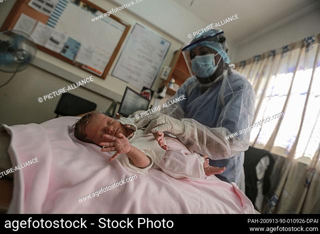 13 September 2020, Palestinian Territories, Gaza: A Palestinian health worker wearing a protective suit gives polio vaccine to a child at a clinic runs by the...