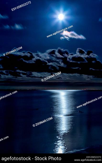 Der Vollmond spiegelt sich nachts im Wattenmeer vor der ostfriesischen Insel Juist, Deutschland. Full moon reflecting on the water at the East Frisian island...