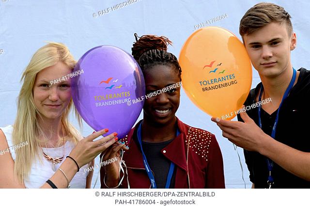 Linda, Jennifer and Max (L-R) hold balloons and look into the camera in the Volkspark in Potsdam, Germany, 16 August 2013