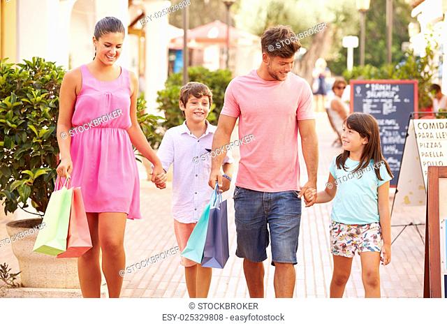 Family Walking Along Street With Shopping Bags