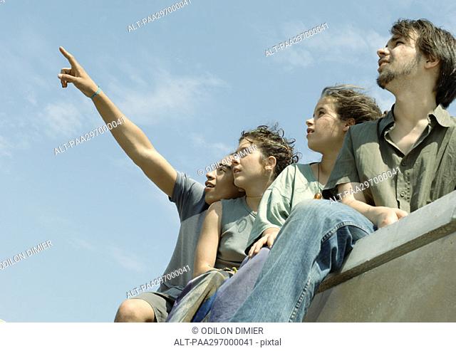 Four young friends standing, looking up at sky