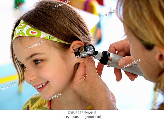 Doctor examining the ears of a 6 years old girl with an otoscope