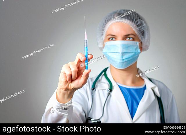 Female doctor with syringe and face mask