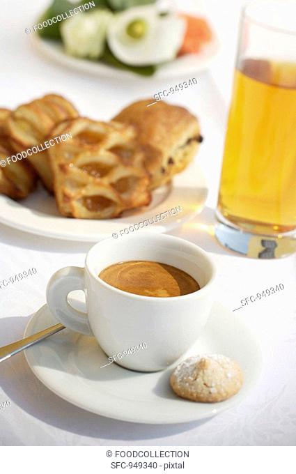 A cup of espresso, apple juice and pastries