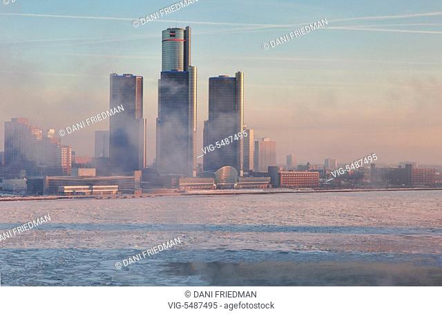 Smoke and fumes from nearby factories shrouds the skyline of downtown Detroit, Michigan, USA. Chunks of ice can be seen floating along the Detroit River