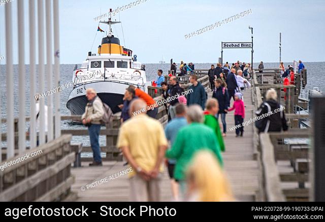 28 July 2022, Mecklenburg-Western Pomerania, Binz: Tourists walk on the pier of the seaside resort of Binz. Exactly 110 years ago - on July 28