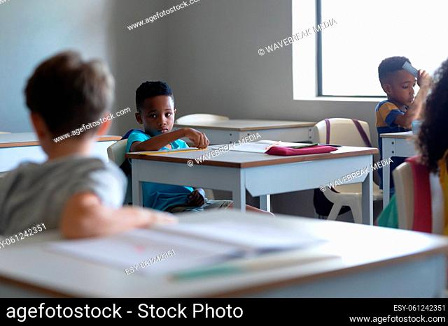 Multiracial elementary school students sitting at desk in classroom