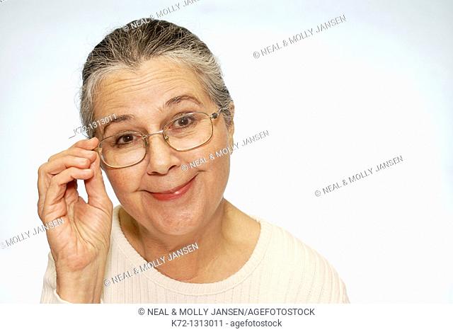 Smiling older woman touching glasses on face