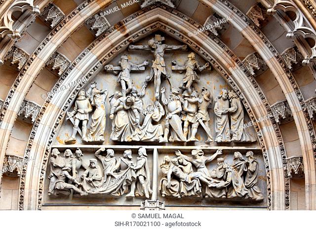 Tympanum Reliefs Above the Bronze Door of the central portal in the St. Vitus Cathedral's western facade, depicting The Crucifixion and a game of dice in order...
