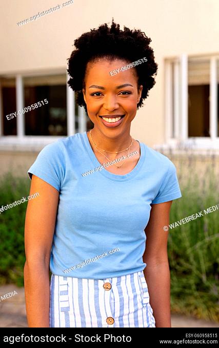 Portrait of happy african american young afro woman smiling while standing outdoors