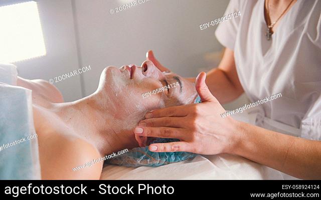 Cosmetologist making a massage for lifting the skin of the client with special device, beauty and self-care concept