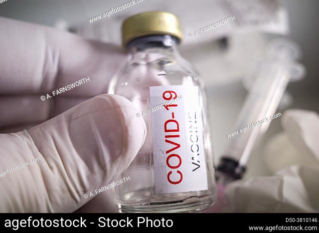 A Covid-19 vaccine flask and a syringe with rubber gloves