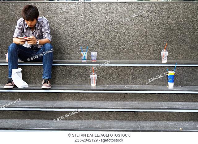 Young Man sitting at Siam Square in Bangkok, Thailand