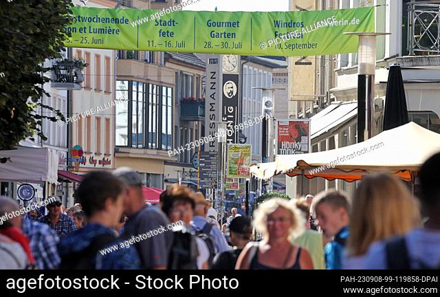 08 September 2023, Mecklenburg-Western Pomerania, Schwerin: In the city center passers-by are under banners and between the stalls